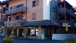 Un edificio de varios pisos con fachada de madera, balcones y un letrero que dice 'Nicolas Thibon Immobilier'.