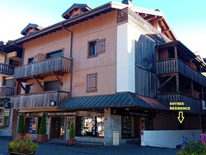 Ein mehrstöckiges Gebäude mit Holzfassade, Balkonen und einem Schild für 'Nicolas Thibon Immobilier'.