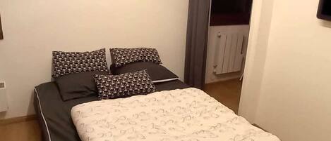 Une chambre à coucher avec un lit, des oreillers et un radiateur.
