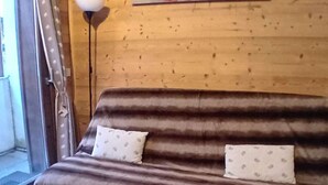 Un sofá marrón con cojines estampados frente a una pared de madera.