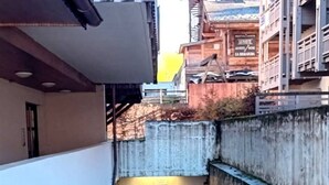 Un callejón estrecho con un edificio blanco a un lado y una construcción de madera al otro.