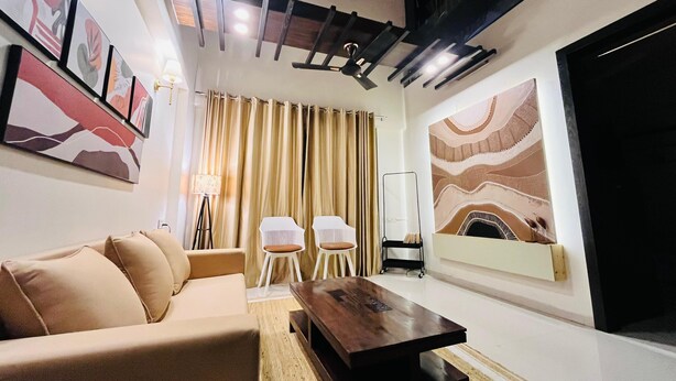 Una sala de estar moderna con un sofá, dos sillones, una mesa de centro y una pantalla de televisión grande.