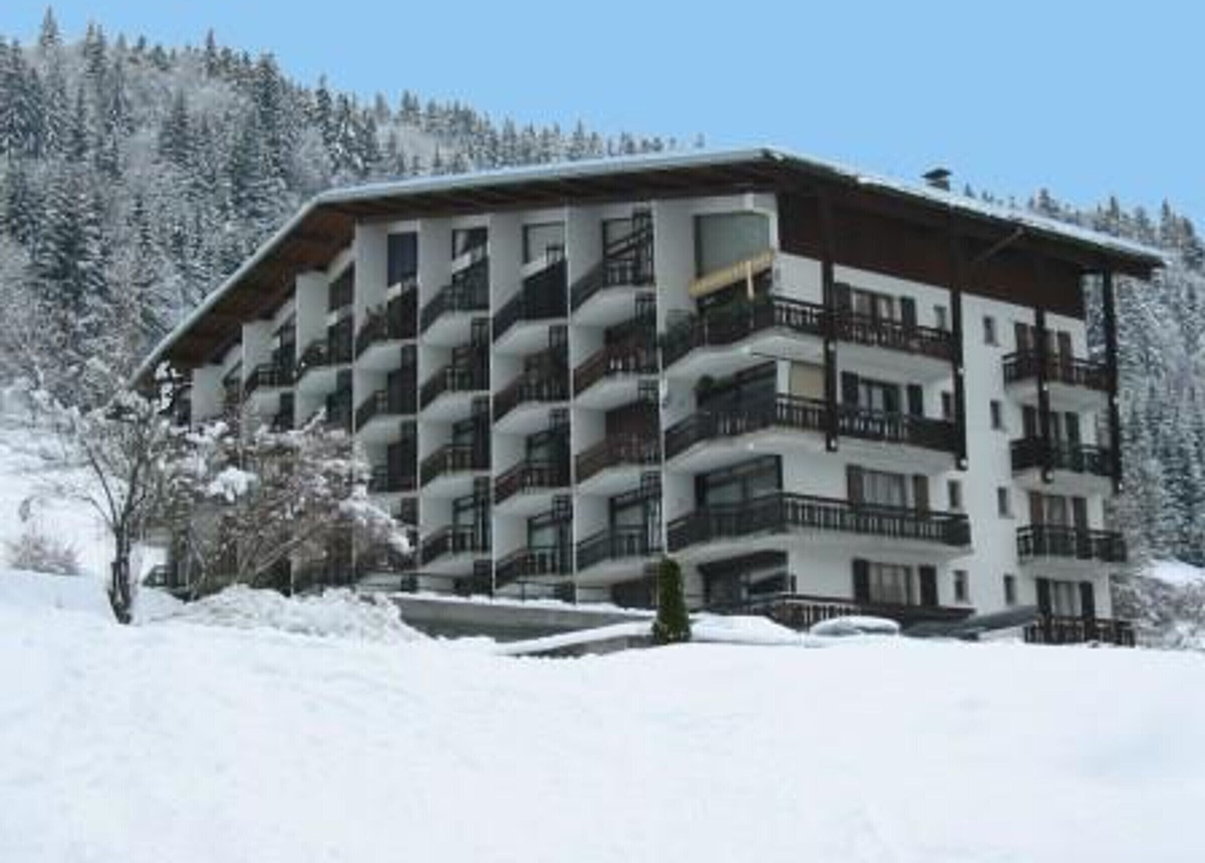 A multi-story hotel with balconies, surrounded by snow-covered trees.