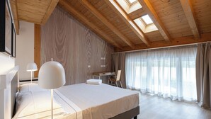 A bedroom with a large bed, a desk, and a chair. There are skylights on the ceiling and a window with curtains. - Agriturismo Sadira  (Calusco d'Adda)