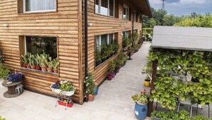 A wooden house with multiple windows and a garden with potted plants. - Agriturismo Sadira  (Calusco d'Adda)