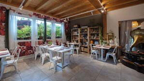 A dining area with wooden beams, white tables, and chairs. There is a piano and a bookshelf with various items. - Agriturismo Sadira  (Calusco d'Adda)