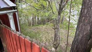 A red wooden fence, a tree, and a building with a red roof. - 4 Person Holiday Home in Tyreso (Tyreso)
