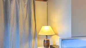 A room with a wooden desk, a lamp, a computer monitor, and a curtain. - 4 Person Holiday Home in Tyreso (Tyreso)