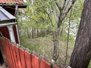 A view from a balcony with a red railing, overlooking a forested area with trees and a body of water. - 4 Person Holiday Home in Tyreso (Tyreso)