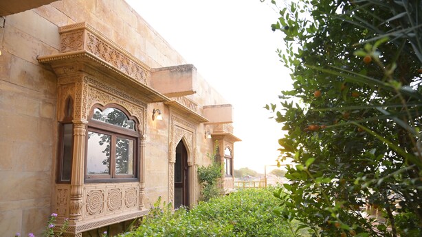 A building with intricate stone carvings and arched windows. - Khushbu haveli hotel and restaurant (Pokhran)