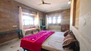 A bedroom with a bed, a bench, a desk, and a window. - Khushbu haveli hotel and restaurant (Pokhran)