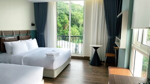 A hotel room with a large bed, a smaller bed, a desk, and a balcony with a view of greenery. - PureJoy Hotel City Center Phu Quoc (Phu Quoc)