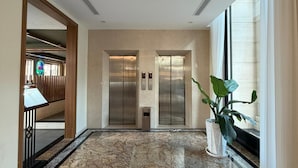 A lobby with two elevators, a reception desk, and a potted plant. - PureJoy Hotel City Center Phu Quoc (Phu Quoc)
