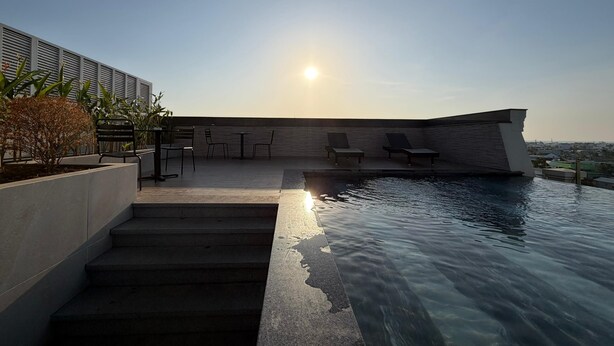 A rooftop pool area with steps leading down to the water, lounge chairs, and a clear view of the city skyline. - PureJoy Hotel City Center Phu Quoc (Phu Quoc)