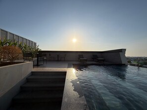 A rooftop pool area with steps leading down to the water, lounge chairs, and a clear view of the city skyline. - PureJoy Hotel City Center Phu Quoc (Phu Quoc)