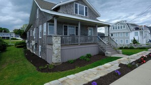 A two-story house with a stone foundation, a front porch, and a small garden with flowers. - Ocean views galore. York Beach at your finger tips (York Beach)