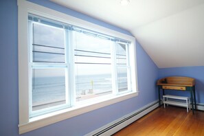 Ein Zimmer mit einem großen Fenster mit Meerblick, einer Holzbank und einem Heizkörper unter dem Fenster.