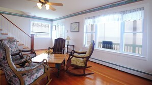 A spacious room with a wooden floor, a dining table, and multiple chairs. There is a ceiling fan, a window with a view, and a staircase leading upstairs. - Ocean views galore. York Beach at your finger tips (York Beach)