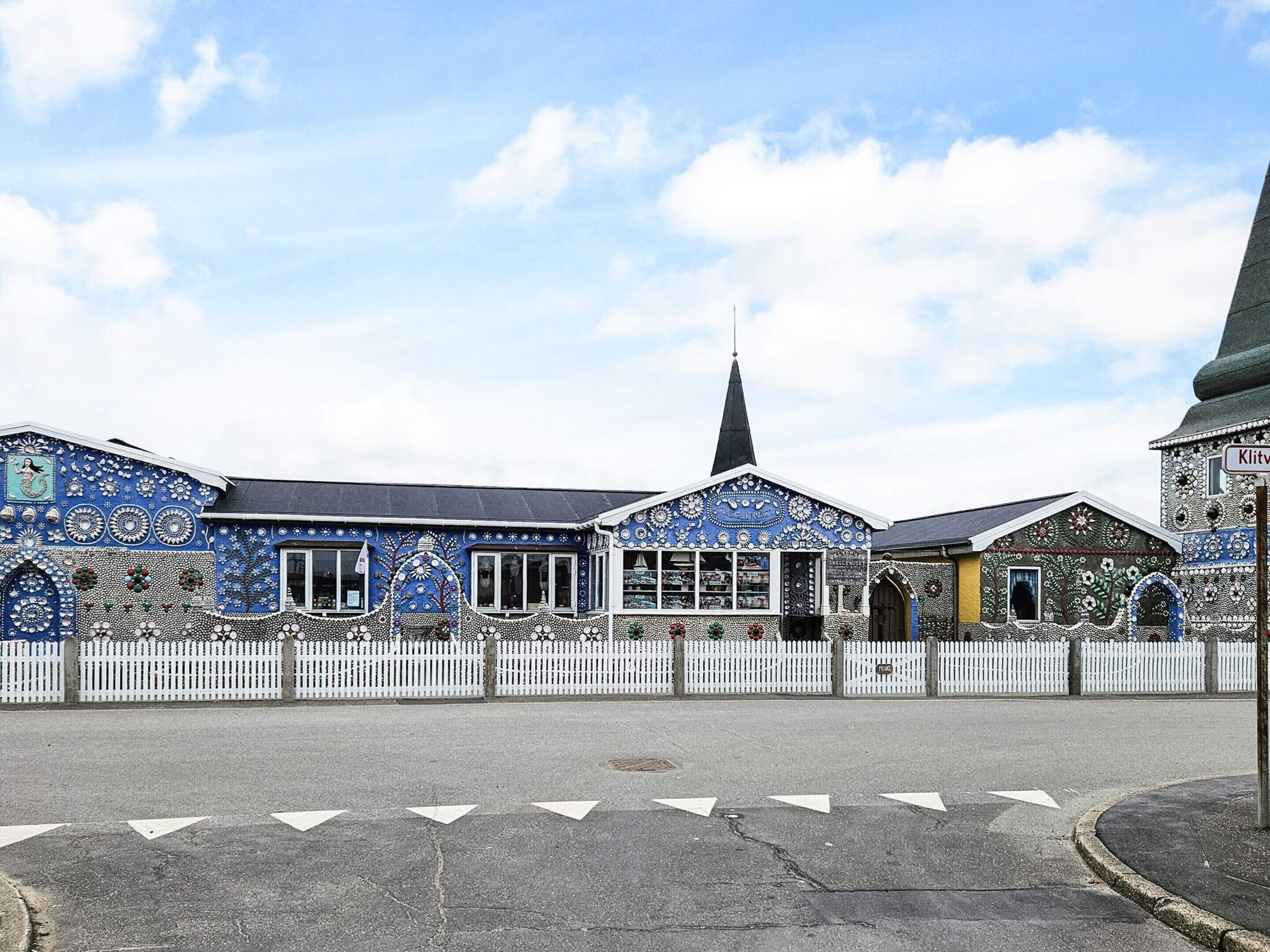 A building with intricate blue and white tilework, a white picket fence, and a church steeple.
