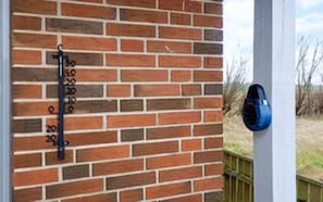 Un mur de briques avec des boîtes aux lettres numérotées, une boîte aux lettres bleue et une clôture en bois en arrière-plan.