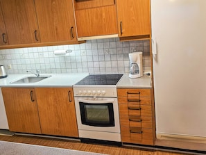 Une cuisine avec des meubles de rangement en bois, un évier, une cuisinière et une machine à café.