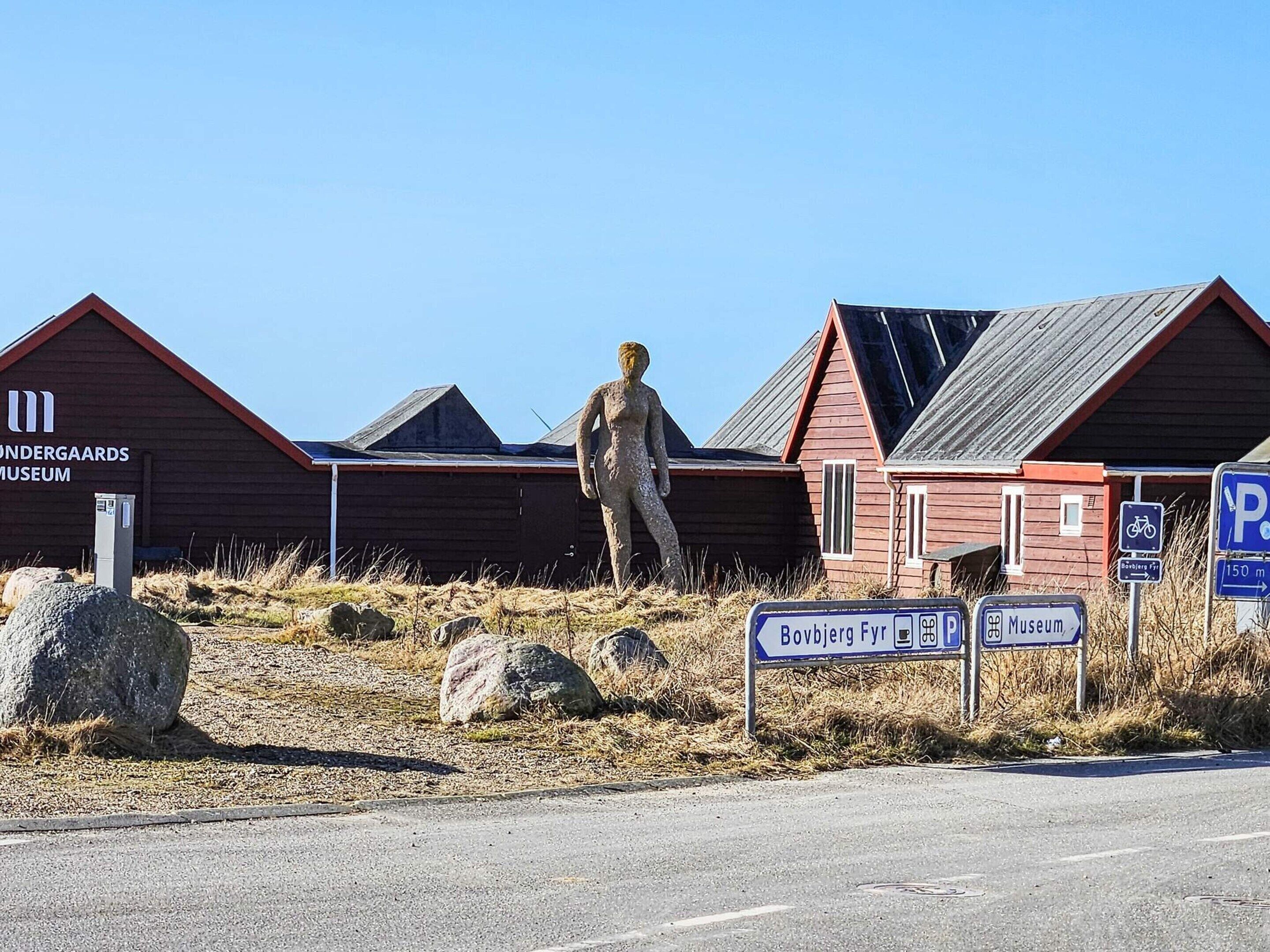 Et museum med en stor udendørs skulptur, en rød bygning og skilte.