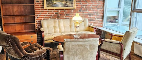 A cozy room with a brick wall, a sofa, a table, and chairs.