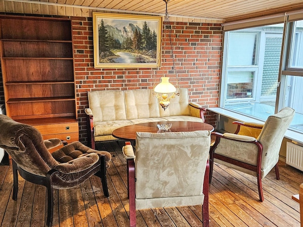 A cozy room with a brick wall, a sofa, a table, and chairs.