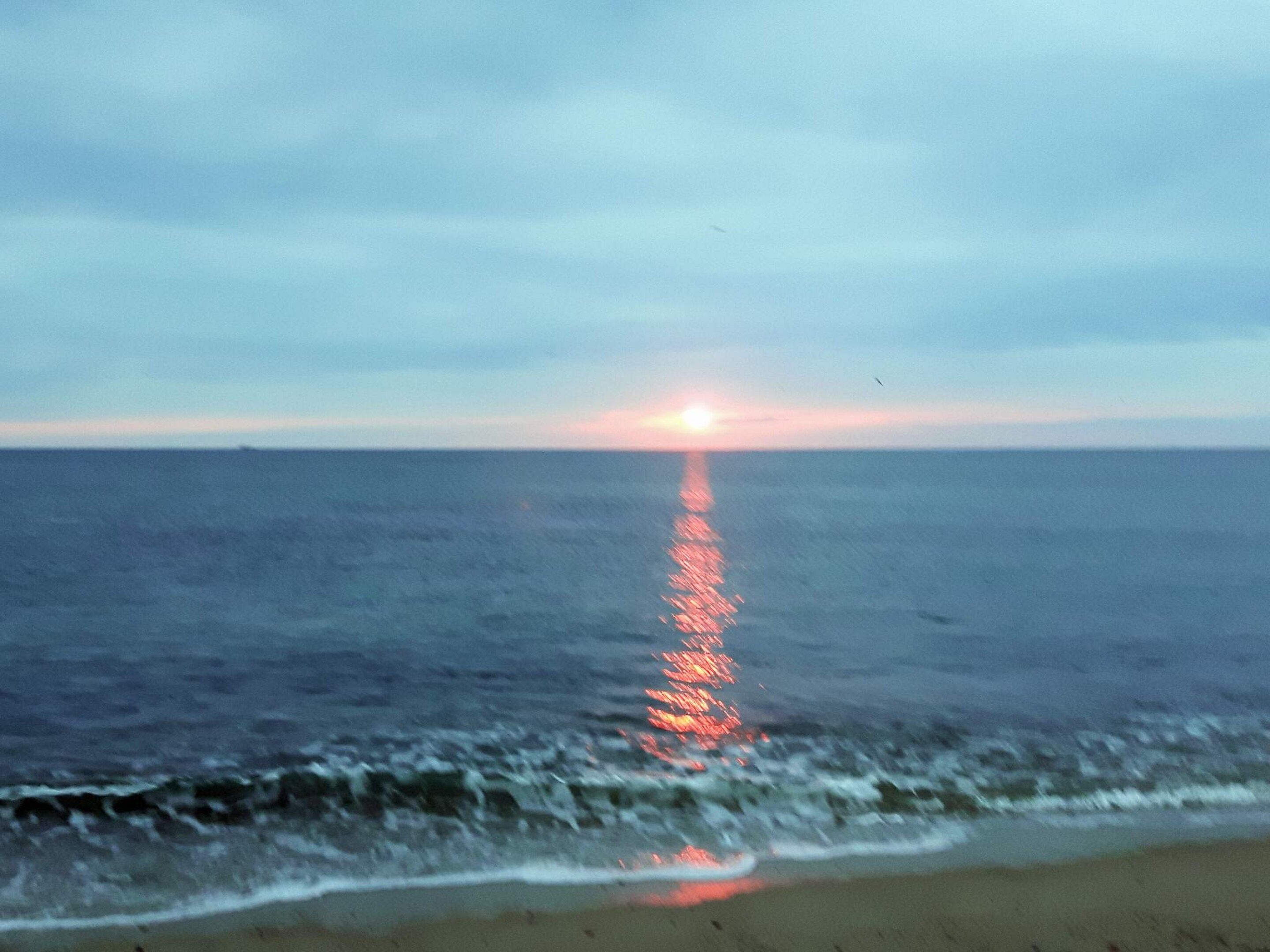 A beach with waves and a sunset.