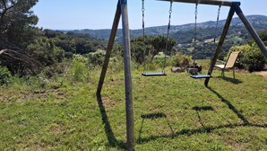 Une balançoire installée dans un espace verdoyant, offrant une vue sur un paysage vallonné.