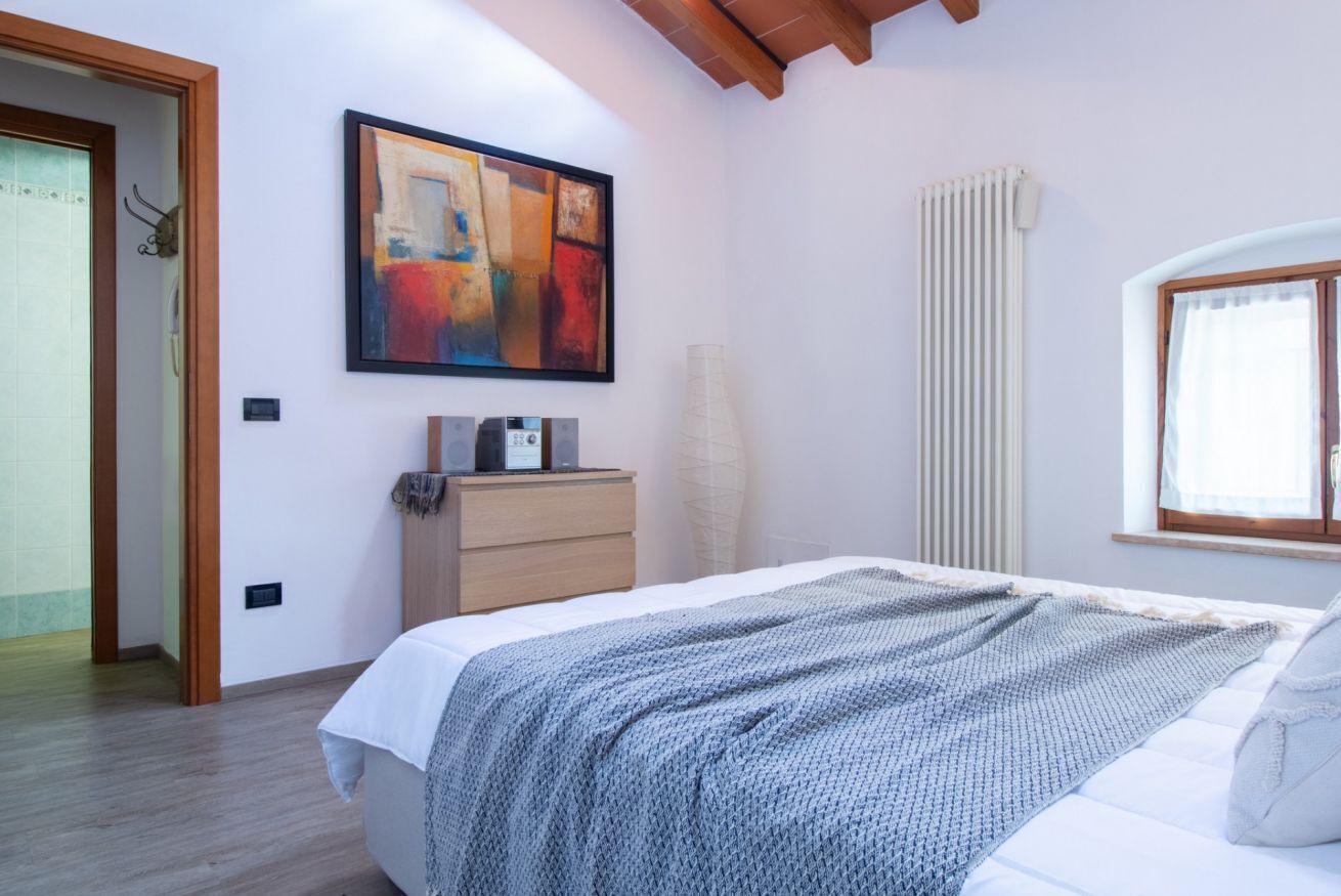 Ein Schlafzimmer mit einem Bett, einem Schminktisch, einem Heizkörper und einem Bild an der Wand.