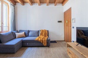 A modern living room with a sectional sofa, a television, and a wooden wardrobe.