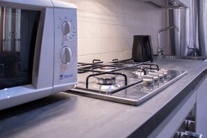 A kitchen with a stove, a coffee maker, and a microwave. - GuestHost - A splendid 65 sq m apartment, perfect for 4 guests, located on the first floor of a completely renovated period building.The accommodation is located in Valeggio sul Mincio, just an 8-minute walk from the Scaligero Castle, a 15-minute walk fr (Valeggio sul Mincio)