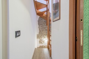 A narrow hallway with a wooden staircase leading to a stone wall. - GuestHost - A splendid 65 sq m apartment, perfect for 4 guests, located on the first floor of a completely renovated period building.The accommodation is located in Valeggio sul Mincio, just an 8-minute walk from the Scaligero Castle, a 15-minute walk fr (Valeggio sul Mincio)