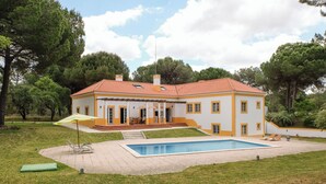 A two-story house with a swimming pool, surrounded by trees and a well-maintained lawn. - UA 78- Villa dos Sobreiros (Alcácer do Sal)