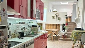 Una cocina moderna con armarios rojos, una encimera blanca y un comedor con mesa y sillas.