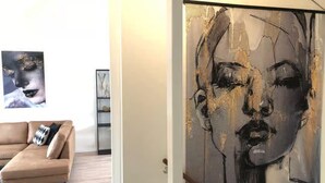 A living room with a beige sofa, a coffee table, and a large abstract painting on the wall. - 5-person Lodge With Private Balcony (Zoutelande)