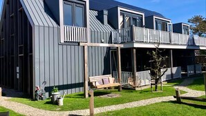 A modern house with a sloped roof, large windows, and a balcony. - 5-person Lodge With Private Balcony (Zoutelande)