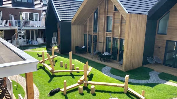 A modern building with a large glass facade, wooden deck, and outdoor seating area. - 5-person Lodge With Private Balcony (Zoutelande)