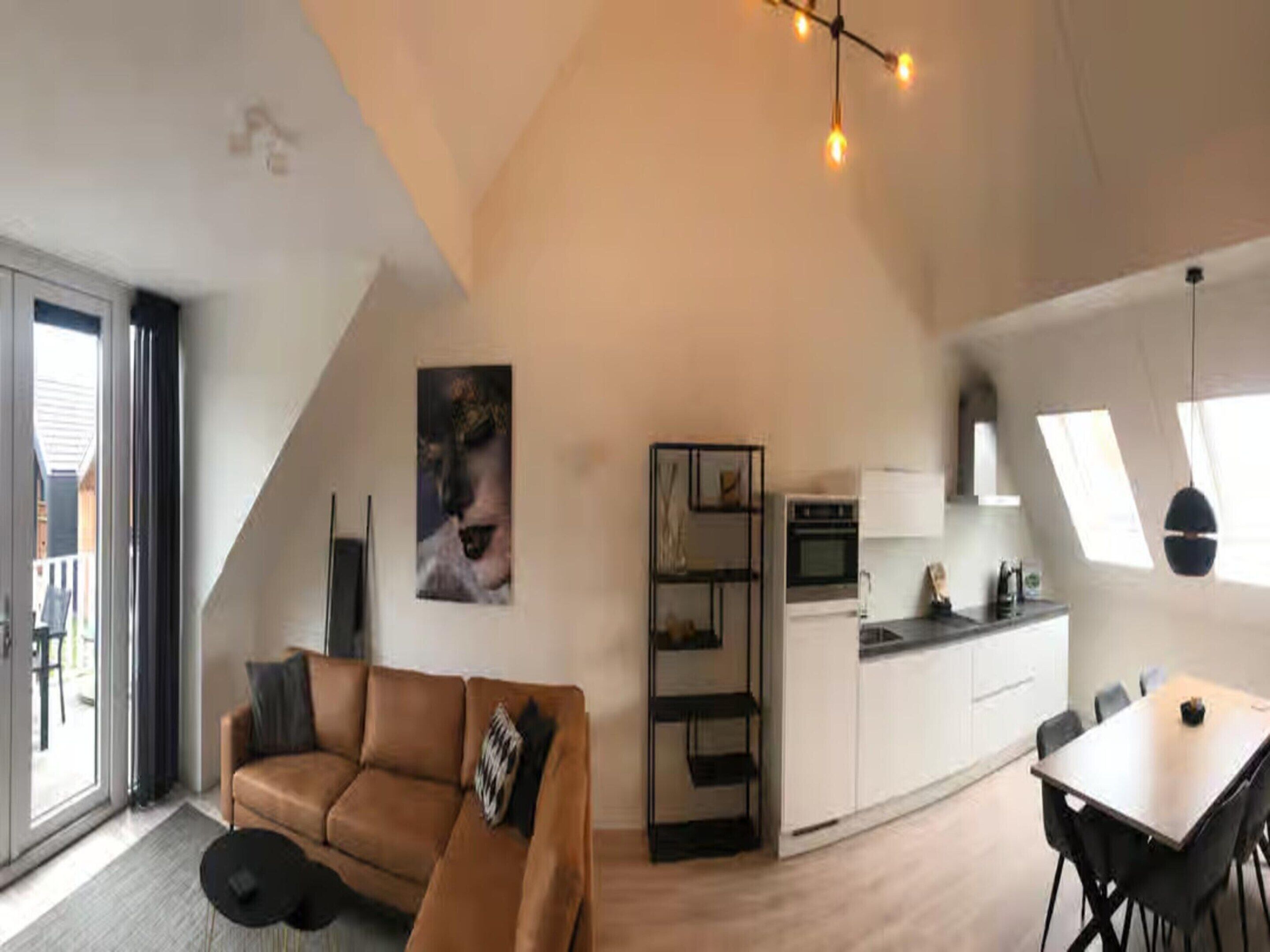 A modern loft-style apartment with a living area, kitchenette, and dining space.