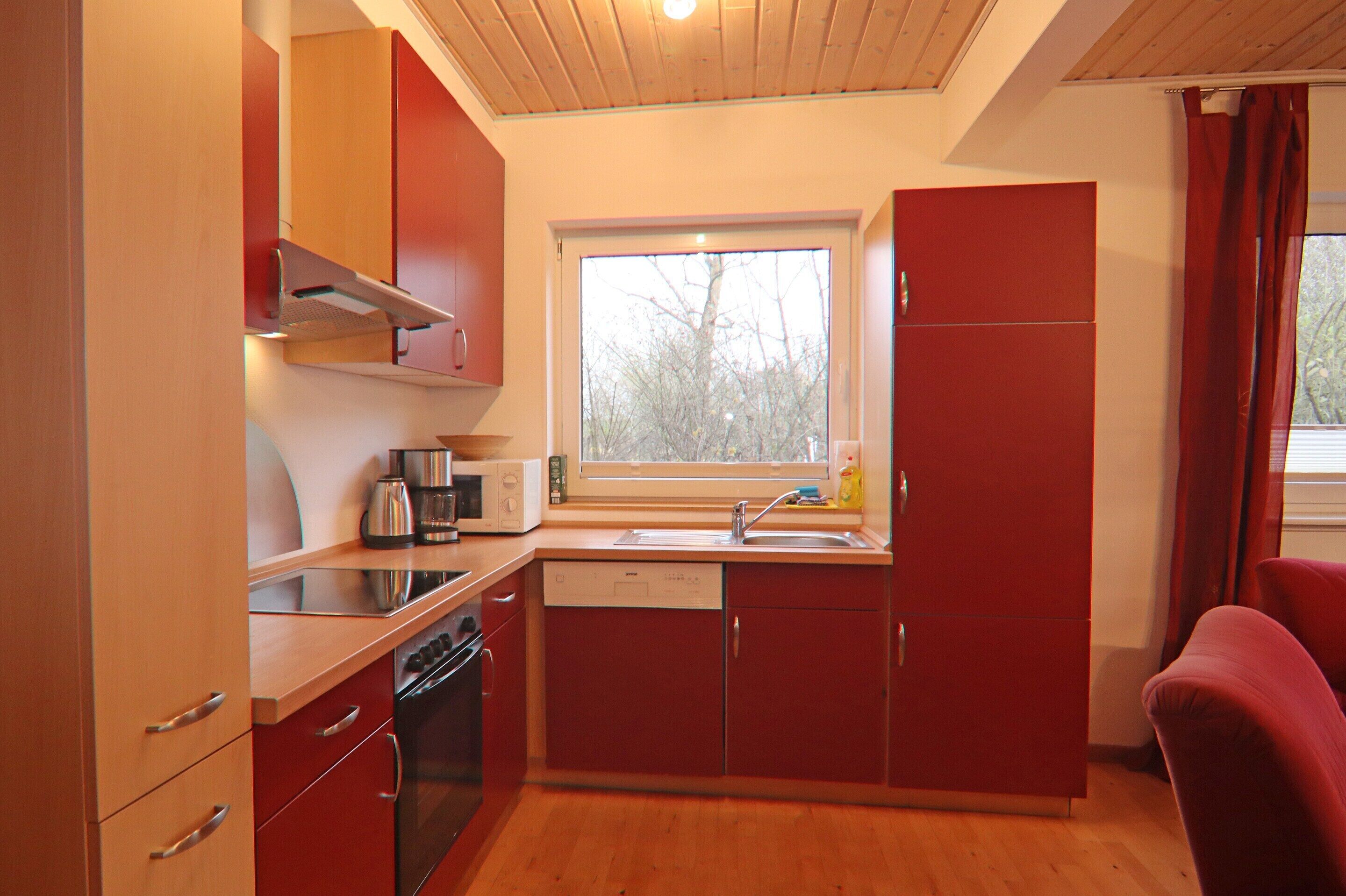 A compact kitchen with wooden cabinets, a dishwasher, a microwave, and a sink.