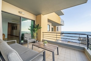 A balcony with a view of the sea, a sofa, a table, and a potted plant. - Apartment 'Ocean Horizon House' with Sea View, Wi-Fi and Air Conditioning (Portimão)