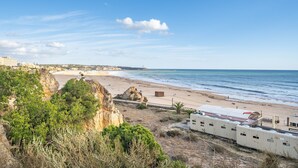 A coastal beach scene with a cliff, beach, and ocean. - Apartment 'Ocean Horizon House' with Sea View, Wi-Fi and Air Conditioning (Portimão)