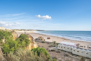 A coastal beach scene with a cliff, beach, and ocean. - Apartment 'Ocean Horizon House' with Sea View, Wi-Fi and Air Conditioning (Portimão)