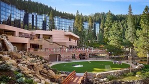 A hotel with a modern architectural style, featuring a large glass facade, a landscaped courtyard with a small pond, and a wooden bridge. - Cozy Fireplace Suite at Everline Resort, Tahoe no resort fee (Olympic Valley)