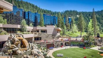 A hotel with a pool, a waterfall, and a tennis court.