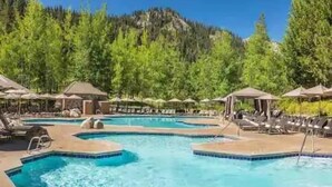 A pool area with multiple swimming pools, lounge chairs, and umbrellas. - Cozy Fireplace Suite at Everline Resort, Tahoe no resort fee (Olympic Valley)