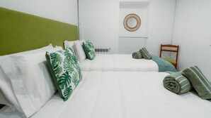 Une chambre d’hôtel bien rangée, avec un lit, des oreillers, une chaise et une petite table.