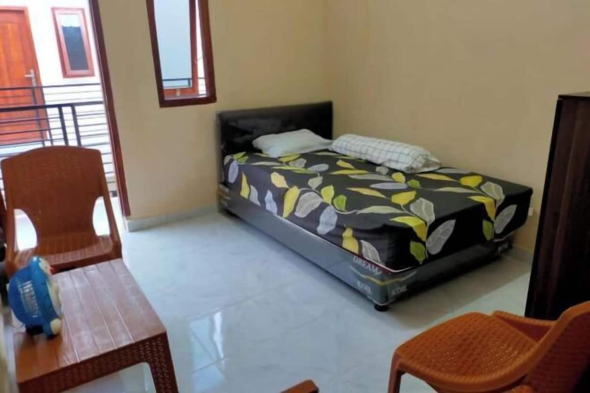 A small, clean room with a bed, a table, and two chairs.