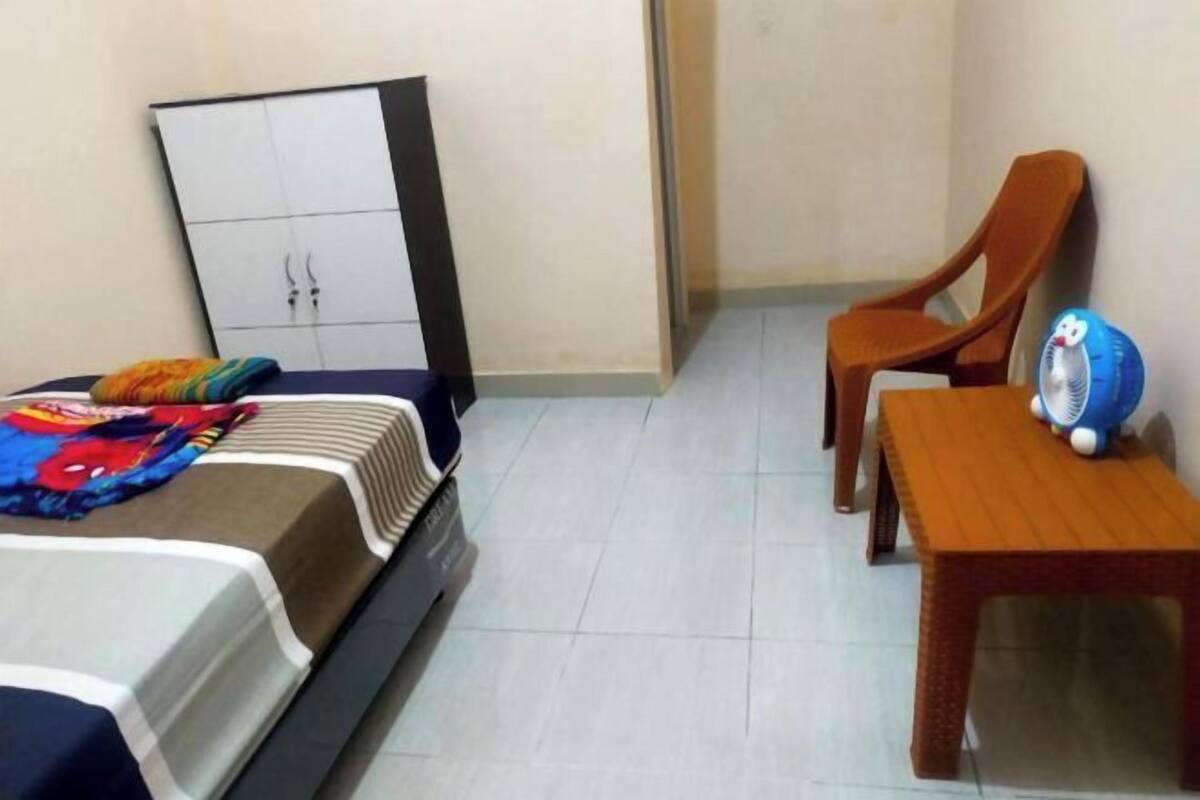 A bedroom with a bed, a wardrobe, a chair, and a small table with a toy.